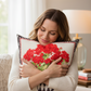 Woman holding a decorative pillow with red floral design in a cozy living room.